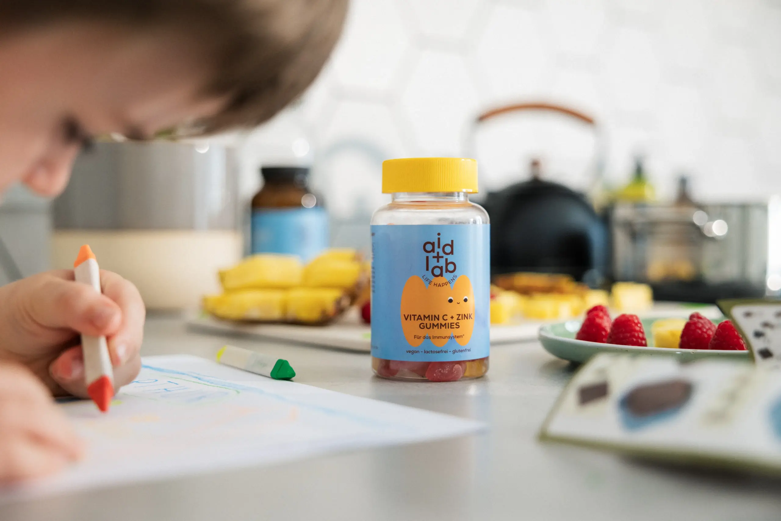 aidlab Vitamin C & Zink Gummies und Kind beim Malen